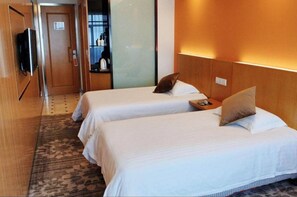 Een hotelkamer met twee bedden, een televisie, een minibar en een zichtbare badkamer achter een glazen deur.