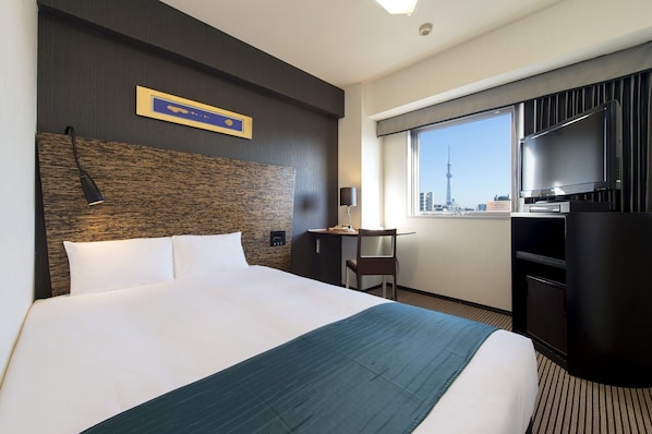 A hotel room with a bed, a desk, a chair, a TV, and a window with a city view. - Hotel Villa Fontaine Tokyo - Ueno Okachimachi (Tokyo)