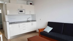 A compact living space with a kitchenette, a sofa, and a coffee table.