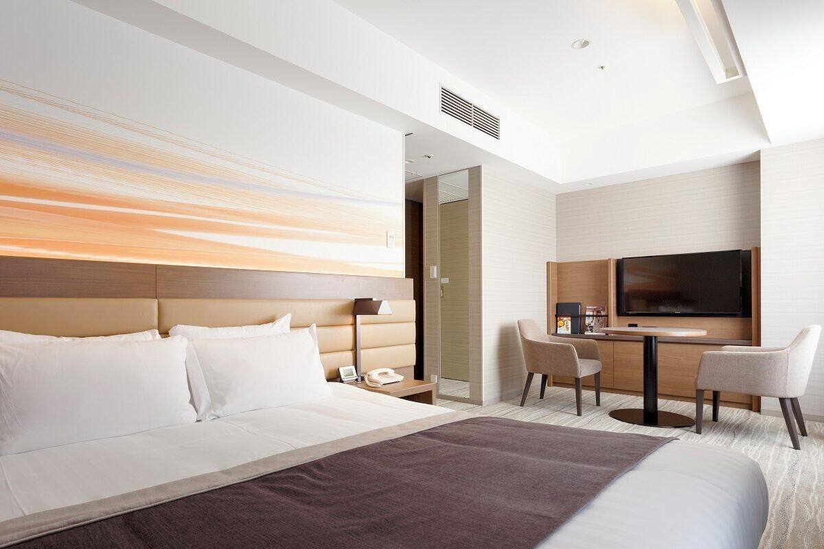 Une chambre d’hôtel avec un grand lit, un bureau avec une télévision et un coin salon.