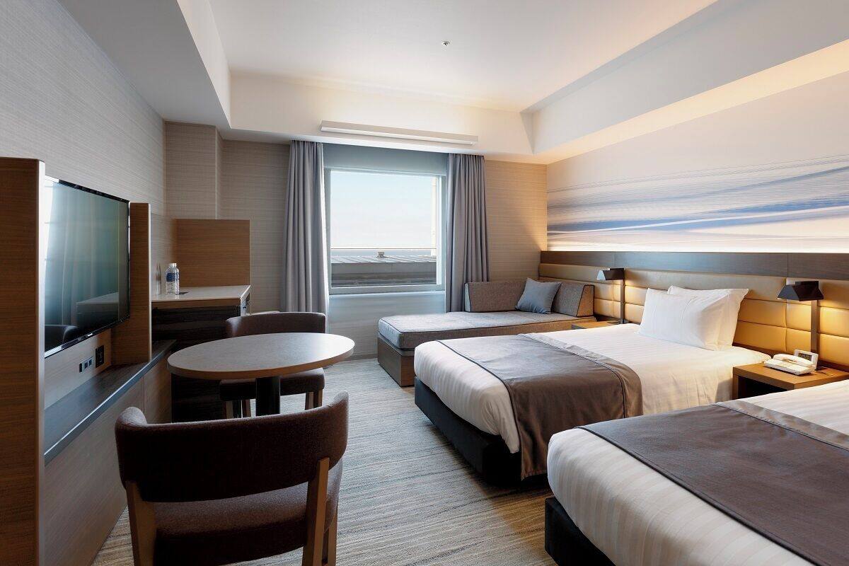 Une chambre d’hôtel équipée d’un lit, d’un bureau, d’une chaise, d’une télévision et d’une fenêtre avec des rideaux.