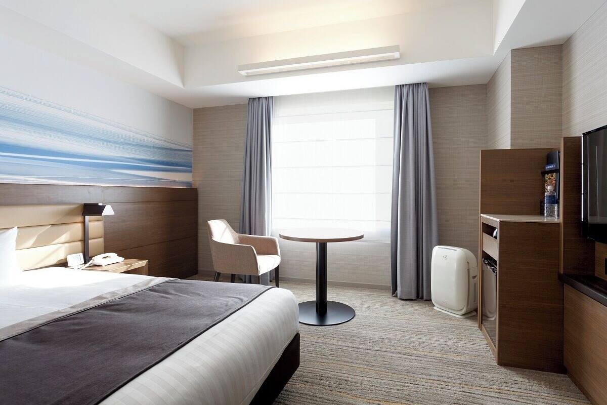 Une chambre d’hôtel équipée d’un lit, d’une table ronde, d’une chaise, d’un téléviseur et d’un mini-bar.