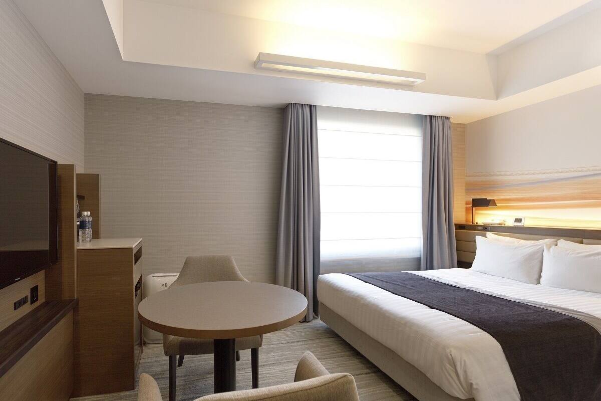 Une chambre d’hôtel avec un lit, une télévision, un bureau et une chaise.