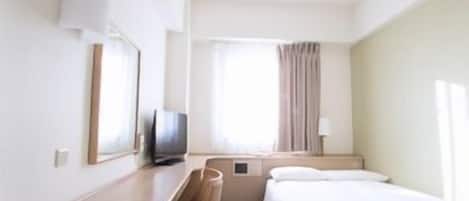 Quarto de hotel com cama, escrivaninha, televisão e janela com cortinas.