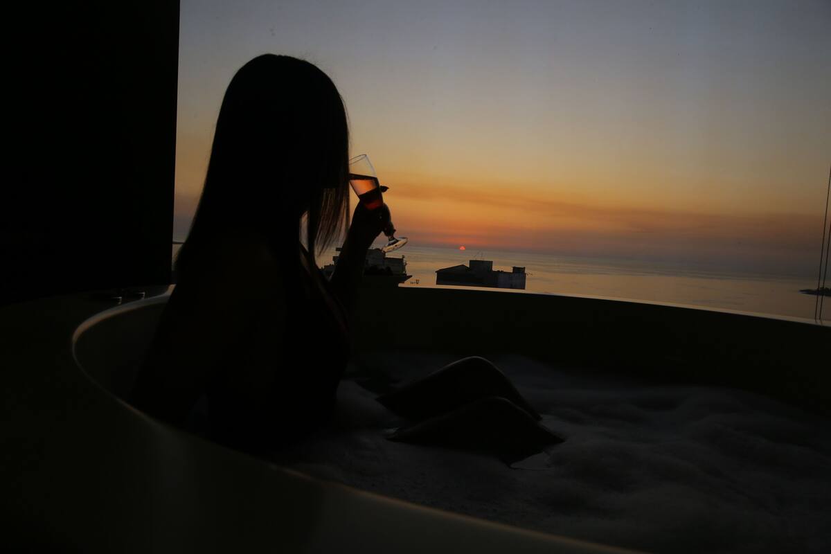 A person in a bathtub with a sunset view.