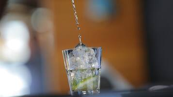A glass with ice cubes and a lime wedge, with water being poured into it.
