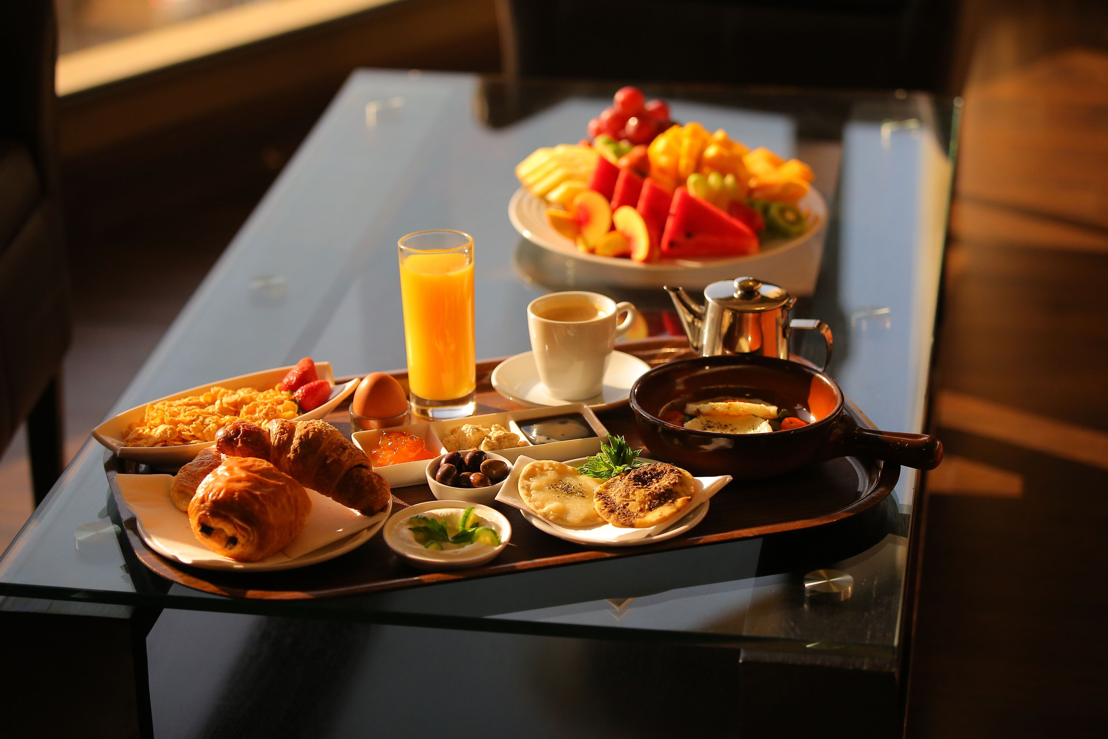 Ein Frühstücksbrett mit Croissants, Obst, Kaffee und einer Suppentasse.