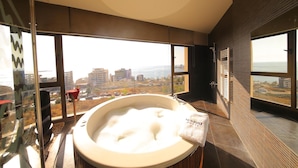 A modern bathroom with a large bathtub, a glass shower enclosure, and a city view. - Sunrise Hotel (Jounieh)
