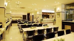 Un restaurant spacieux, doté de nombreuses tables et chaises, d’un comptoir avec un ordinateur portable, et d’un intérieur propre et moderne.