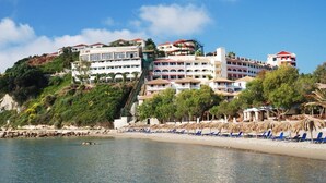 A coastal hotel with multiple buildings, a beach with sun loungers, and a clear sky. - Zante Imperial Beach Hotel (Zakynthos)