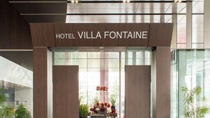 The entrance to Hotel Villa Fontaine with a modern design, featuring a glass facade and a reception desk with a floral arrangement. - Hotel Villa Fontaine Grand Tokyo-Tamachi (Tokyo)