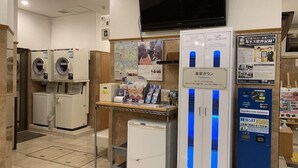 Un vestíbulo de hotel con un televisor montado en la pared, un mostrador de recepción y una máquina expendedora.