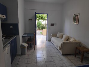 Un espacio habitable compacto con kitchenette, comedor y sofá.