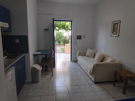 Un espacio habitable compacto con kitchenette, comedor y sofá.