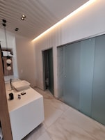 Un baño moderno con tocador blanco, un espejo grande y una cabina de ducha de vidrio.