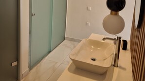 Un baño moderno con un espejo grande, una lámpara de pared y una puerta corredera de techo a piso.
