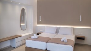 Une chambre d’hôtel moderne avec un lit double, des tables de chevet, un banc et un grand miroir.