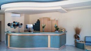 Un espace d’accueil doté d’un comptoir incurvé, d’un climatiseur fixé au mur, d’un téléviseur et d’un mur décoratif orné d’objets circulaires.