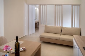 A modern living room with a sofa, a coffee table, and a bottle of wine. - Papadakis Apartments (Apokoronas)