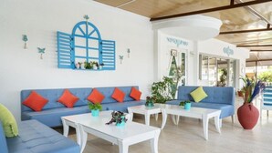 A modern living room with blue sofas, white coffee tables, and decorative plants. - Ramira Beach Hotel (Alanya)