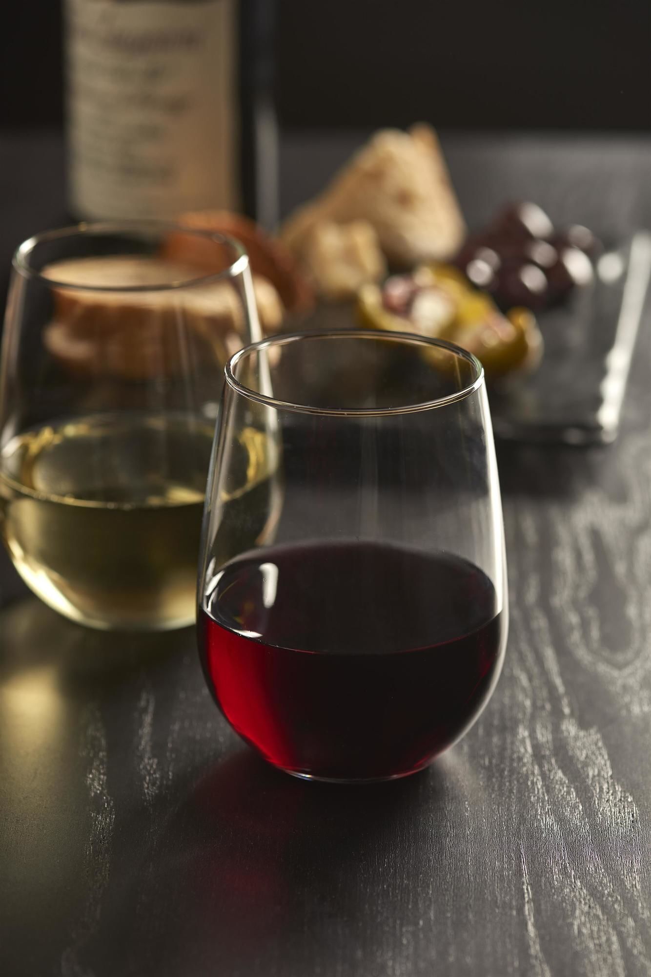 Two glasses of wine on a wooden surface, one with white wine and the other with red wine.