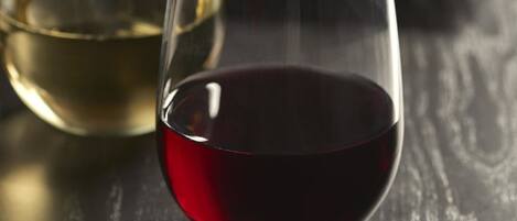 Dos copas de vino sobre una superficie de madera, una con vino blanco y otra con vino tinto.