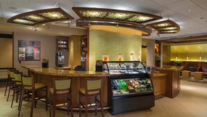 A bar area with a counter, stools, a refrigerated display case, and a menu board. - Hyatt Place Reno Tahoe Airport (Reno)