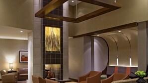 A modern lobby with leather sofas, a central table, and a decorative wall with a tall plant. - Hyatt Place Reno Tahoe Airport (Reno)