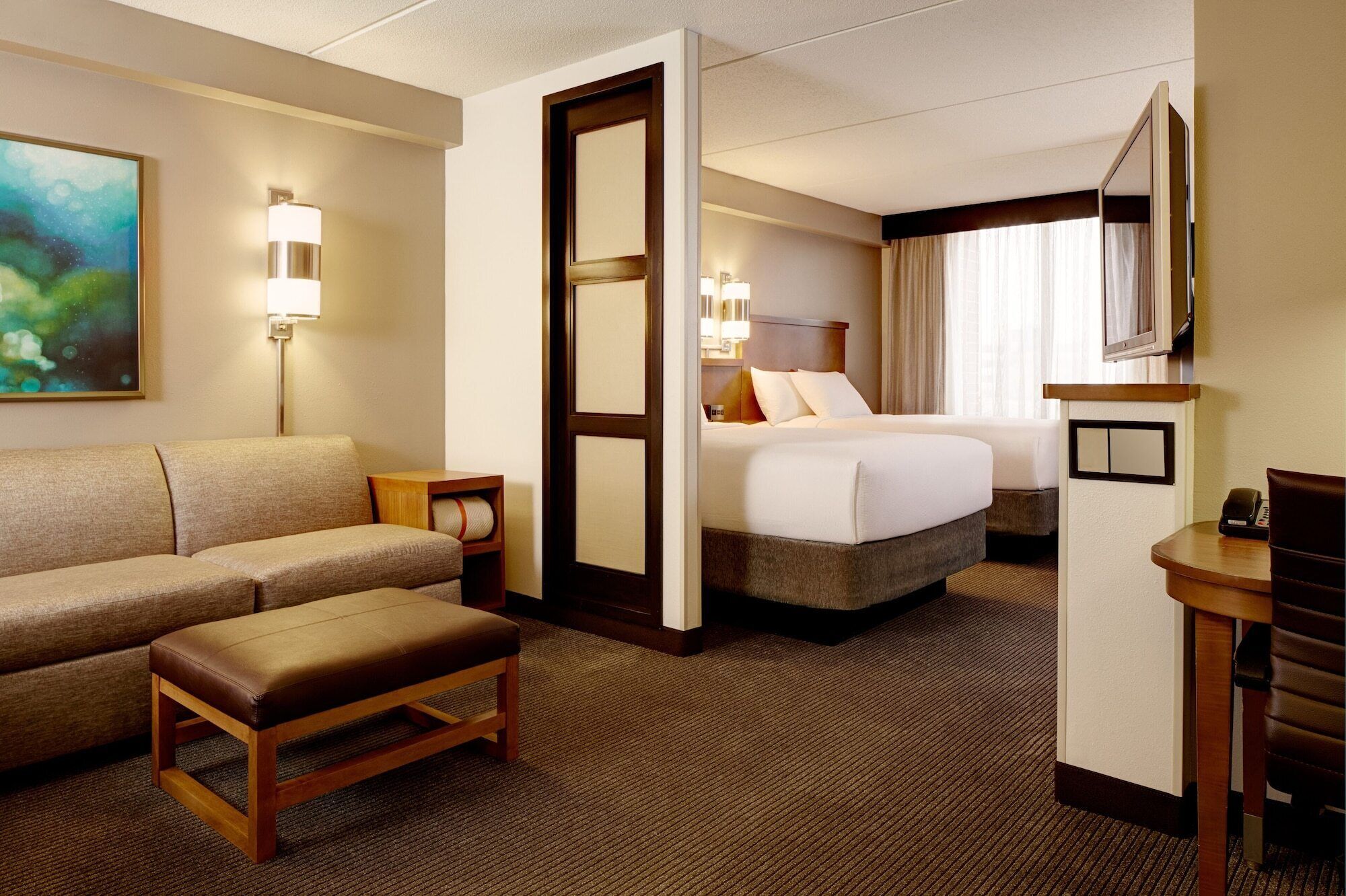 Une chambre d’hôtel avec un canapé, un lit, un bureau et une télévision.