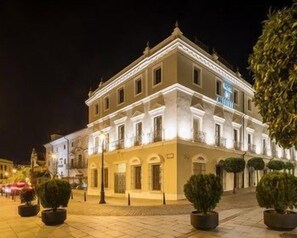 Un edificio con fachada simétrica, varias ventanas y una entrada central.