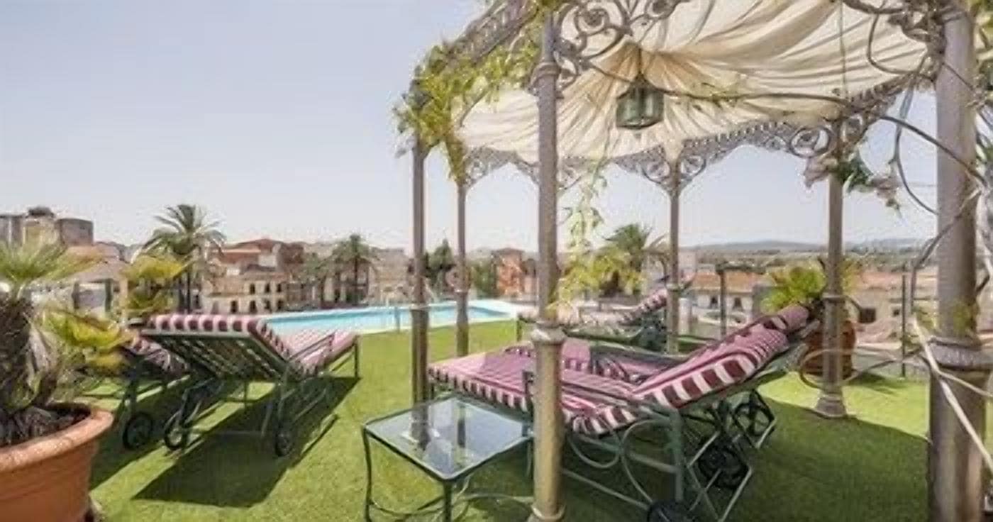 Una terraza en la azotea con piscina, sillones de descanso y una pérgola.