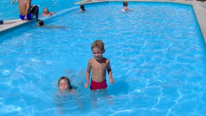A swimming pool with multiple people in the water.