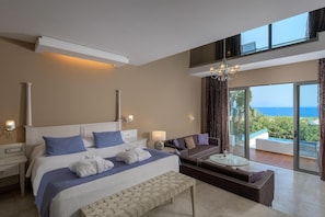 Une chambre d’hôtel moderne dotée d’un grand lit, d’un canapé, d’une petite table et d’un balcon offrant une vue sur la mer.
