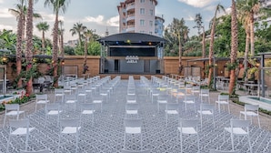 An outdoor seating area with white chairs and a stage in the background. - Aria Resort & Spa Hotel (Alanya)