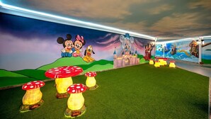 A room with a mural of Disney characters, artificial grass, and illuminated mushroom stools. - Aria Resort & Spa Hotel (Alanya)