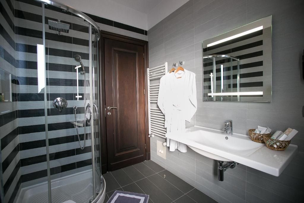 Ein modernes Badezimmer mit Duschkabine aus Glas, einem weißen Waschbecken mit Spiegel und einem Handtuchhalter.