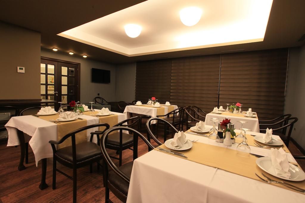 A dining area with tables set for service, chairs, and a ceiling light fixture.