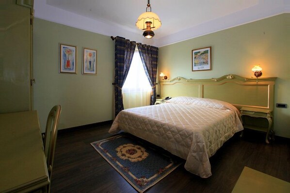 A bedroom with a bed, a nightstand, a chair, a rug, and a window with curtains.