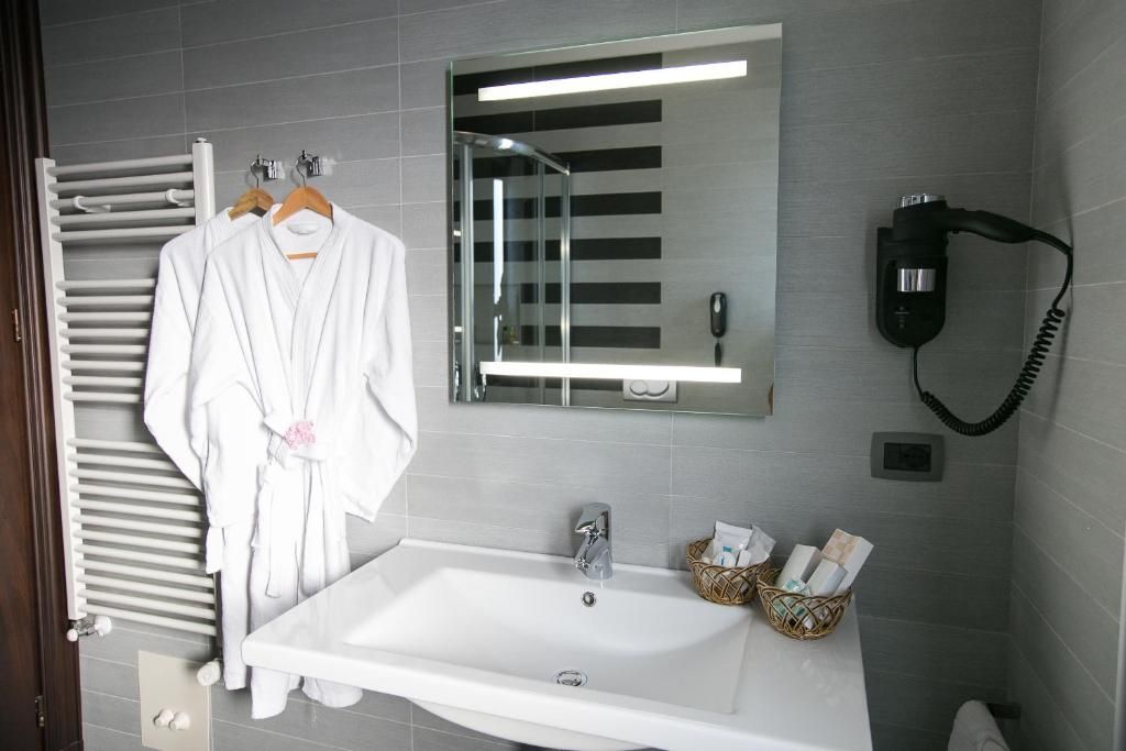 A bathroom with a white sink, a mirror, a towel rack, and a hairdryer.