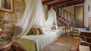 A rustic room with a stone wall, a wooden staircase, and a bed with a canopy. - Casa Di Veneto (Hersonissos)