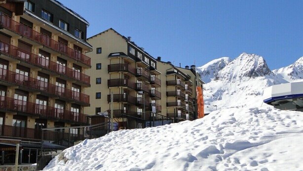 A multi-story hotel with balconies and a snowy mountain backdrop.