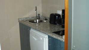 A compact kitchen with a built-in dishwasher, a sink, and a toaster.