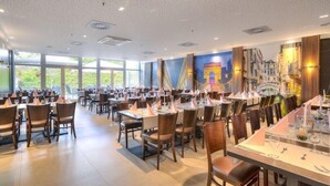 A spacious restaurant with multiple dining tables and chairs, large windows, and a mural of the Eiffel Tower. - Achat Hotel Frankfurt Maintal (Maintal)