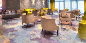 A modern lounge area with plush seating, a glass coffee table, and a patterned carpet. - Achat Hotel Frankfurt Maintal (Maintal)