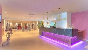 A reception area with a modern counter, a reception desk, and a welcoming sign. - Achat Hotel Frankfurt Maintal (Maintal)