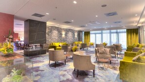 A spacious lobby with multiple seating areas, a reception desk, and a large window providing natural light. - Achat Hotel Frankfurt Maintal (Maintal)