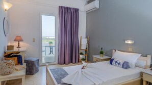 A bedroom with a bed, bedside table, lamp, and a view of the outdoors through a window with purple curtains. - Pasiphae (Heraklion)
