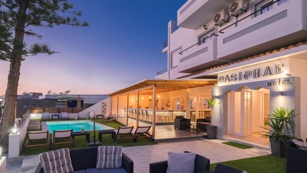 A modern hotel with a pool, outdoor seating, and a bar area. - Pasiphae (Heraklion)