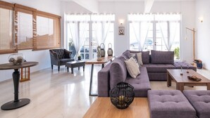 A modern living room with a sectional sofa, a round coffee table, and a wooden side table. - Pasiphae (Heraklion)