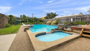 A backyard with a swimming pool, a wooden deck, and a brick wall. - Comfort Inn and Suites Lakes Entrance (Lakes Entrance)
